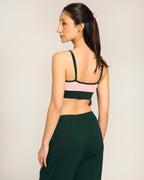 Woman wearing a sports bra by Buttah and leggings on a plain background - rear view