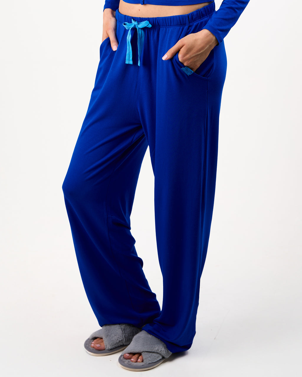 Person wearing blue pajama pants with a white background

