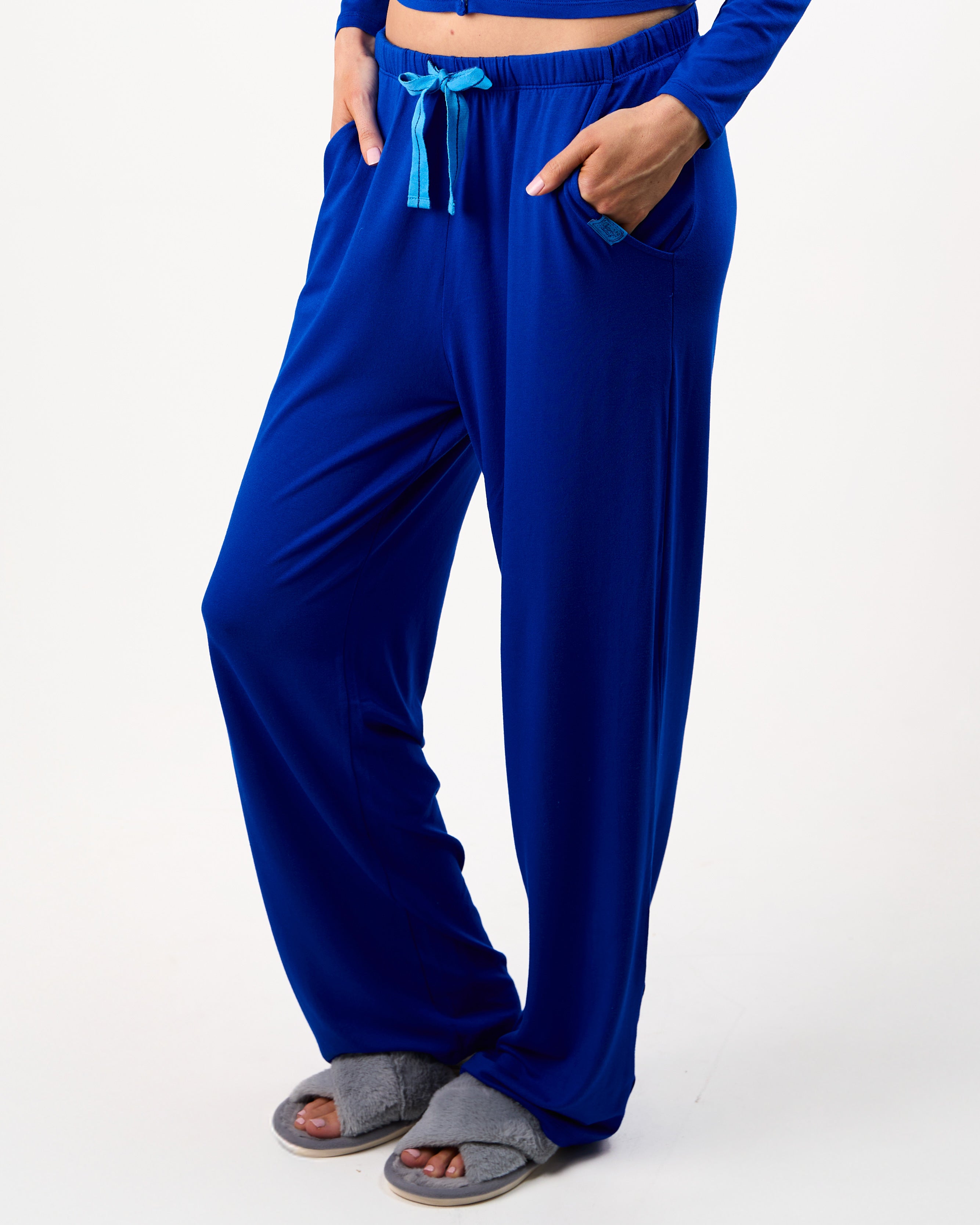 Person wearing blue pajama pants with a white background

