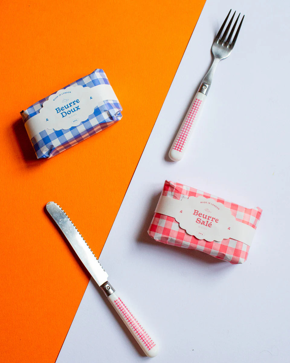 Two butter candles labeled 'Beurre Doux' and 'Beurre Sale' with a knife and fork on an orange and white background.