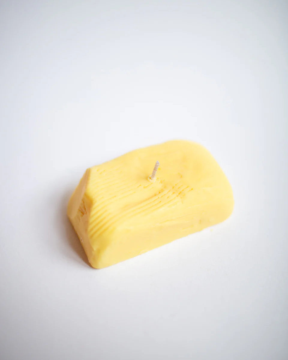 Yellow butter candle shaped like a block on a white background